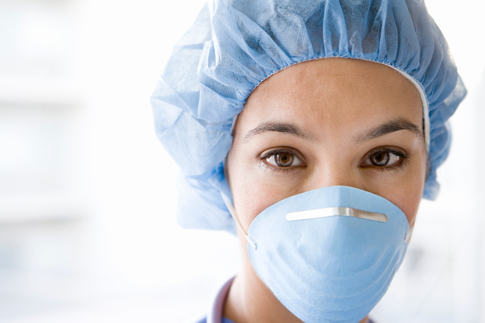 Young female nurse at camera wearing surgical mask